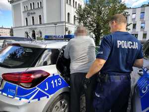 policjant prowadzi zatrzymanego do radiowozu