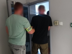 policjant prowadzi zatrzymanego