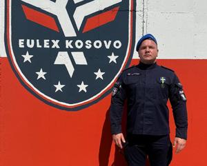 Policjant na tle herbu Eulex Kosowo