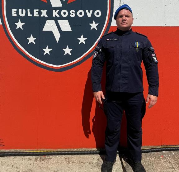 Policjant na tle herbu Eulex Kosowo