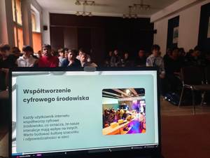 ekran laptopa, w tle młodzież