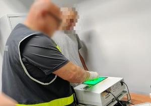 policjant skanuje odciski palów zatrzymanemu