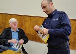 policjant przekazuje ulotkę seniorowi