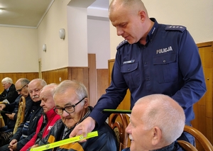 policjant przekazuje ulotkę seniorowi