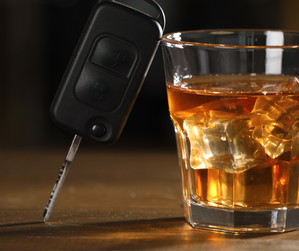 kluczyki od pojazdu obok szklanki z napojem