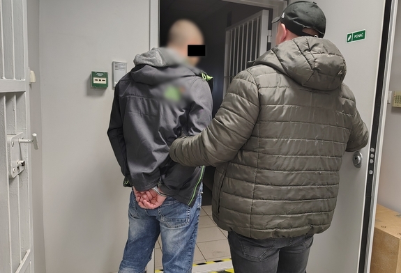 policjant wprowadza zatrzymanego do pomieszczenia dla osób zatrzymanych