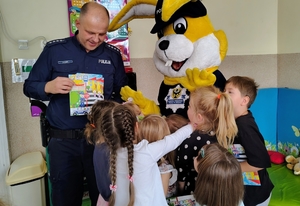 policjant prezentuje dzieciom książeczkę