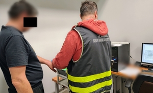 technik kryminalistyki skanuje odciski palców zatrzymanemu