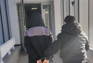 policjant prowadzi zatrzymanego