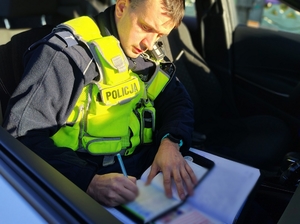 policjant sporządza dokumentację w radiowozie