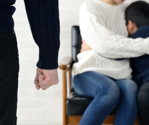 kobieta przytula dziecko, przed nimi zaciśnięta pięść