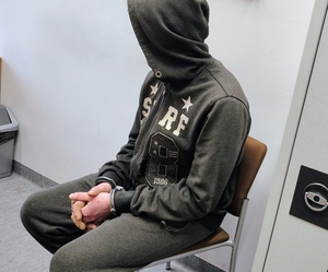 mężczyzna z założonym kapturem siedzi na krześle