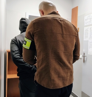 policjant zapina kajdanki zatrzymanemu