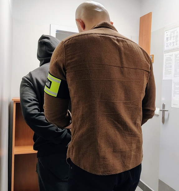 policjant zapina kajdanki zatrzymanemu