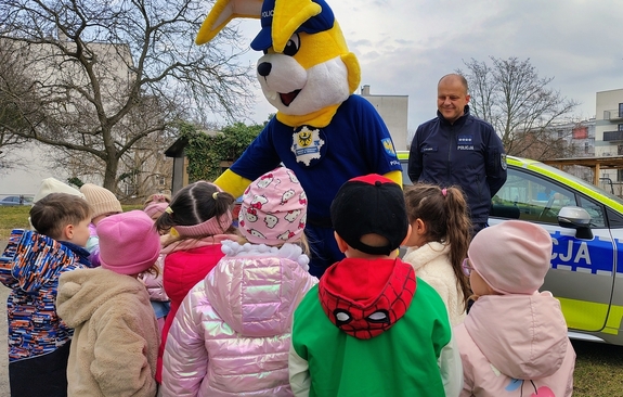 policjant z grupą dzieci i policyjną maskotką