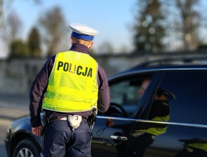 policjant w żółtej kamizelce kontroluje samochód