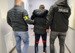 nieumundurowani policjanci prowadzą zatrzymanego
