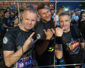 trójka uśmiechniętych mężczyzn w tłumie ludzi
