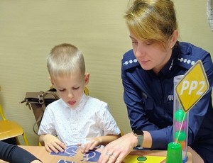 policjantka z chłopcem układa puzle