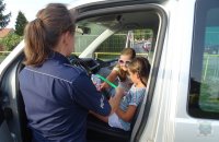 policjantka przekazuje dzieciom odblaski i ulotki promocyjne
