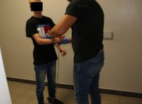 policjant zakłada kajdanki zatrzymanemu