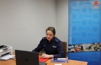 policjanta siedzi przy biuru na którym stoi laptop