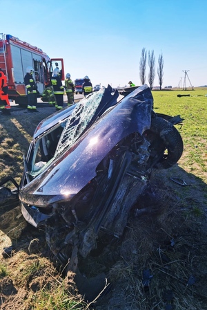Zdjęcie przedstawia samochód po wypadku drogowym, z licznymi uszkodzeniami.