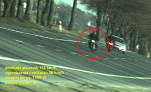 Zdjęcie przedstawia motocyklistę, który przekroczył dopuszczalną prędkość, obok niego znajduje się inny motocyklista oraz pojazd osobowy.