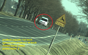 Zdjęcie przedstawia samochód koloru białego, który przekroczył dopuszczalną prędkość.