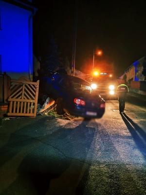 Zdjęcie przedstawia samochód, który wjechał w ogrodzenie domu.