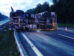 Zdjęcie przedstawia przewróconą ciężarówkę na autostradzie.