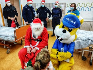 Zdjęcie przedstawia spotkanie policjantów, strażaka, Policusia i Mikołaja z dziećmi w szpitalu.