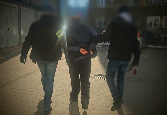 policjanci kryminalni prowadzą zatrzymanego
