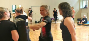 Zdjęcie kolorowe przedstawiające zajęcia samoobrony prowadzone przez strzelecką policjantkę.