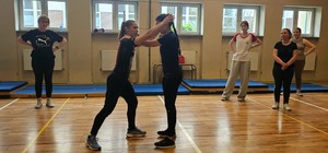 Zdjęcie kolorowe przedstawiające zajęcia samoobrony prowadzone przez strzelecką policjantkę.
