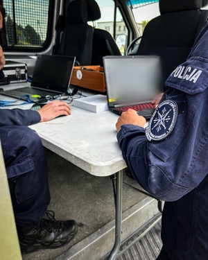 Dwóch policjantów analizuje dane na laptopie.