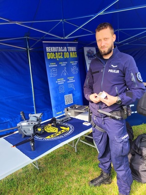 Zdjęcie kolorowe przedstawiające policjanta z dronem.