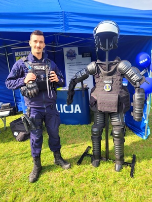 Zdjęcie kolorowe przedstawiające policjanta ze sprzętem policyjnym.