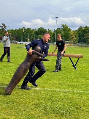 Zdjęcie kolorowe przedstawiające policjanta biorącego udział w konkurencji sportowej.