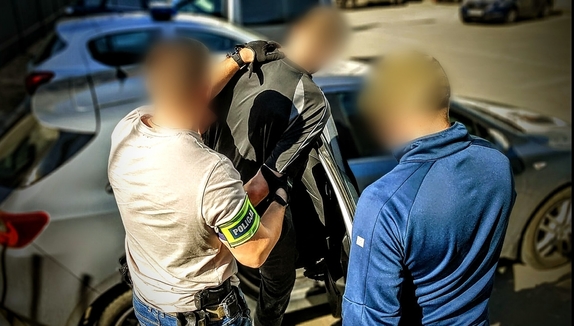 Zdjęcie kolorowe przedstawiające zatrzymanego i dwóch policjantów kryminalnych.