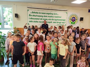 Zdjęcie kolorowe przedstawiające policjanta z dziećmi na spotkaniu edukacyjnym.