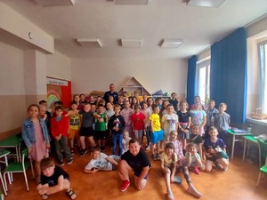 Zdjęcie kolorowe przedstawiające policjanta z dziećmi na spotkaniu edukacyjnym.
