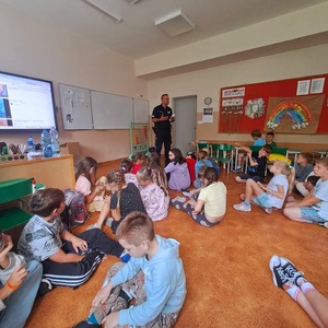 Zdjęcie kolorowe przedstawiające policjanta z dziećmi na spotkaniu edukacyjnym.