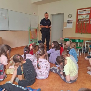 Zdjęcie kolorowe przedstawiające policjanta z dziećmi na spotkaniu edukacyjnym.