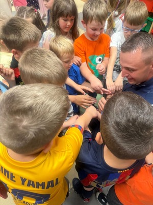 Zdjęcie kolorowe przedstawiające policjanta z dziećmi na spotkaniu edukacyjnym.