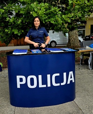 Zdjęcie kolorowe przedstawiające policjantkę przy stoisku promocyjnym.