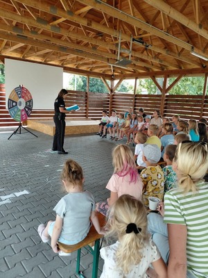 Zdjęcie kolorowe przedstawiające policjantów z dziećmi na spotkaniu w ramach programu &quot;Kręci mnie bezpieczeństwo w lecie&quot;.