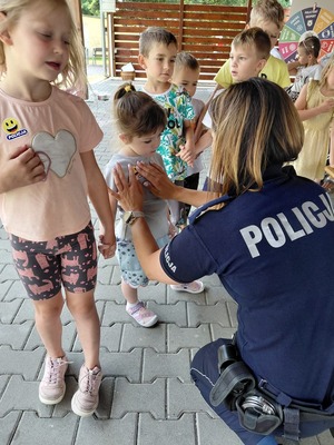 Zdjęcie kolorowe przedstawiające policjantów z dziećmi na spotkaniu w ramach programu &quot;Kręci mnie bezpieczeństwo w lecie&quot;.
