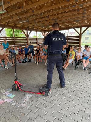 Zdjęcie kolorowe przedstawiające policjantów z dziećmi na spotkaniu w ramach programu &quot;Kręci mnie bezpieczeństwo w lecie&quot;.