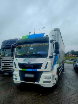 Zdjęcie kolorowe przedstawiające pojazd ciężarowy Man i radiowóz.